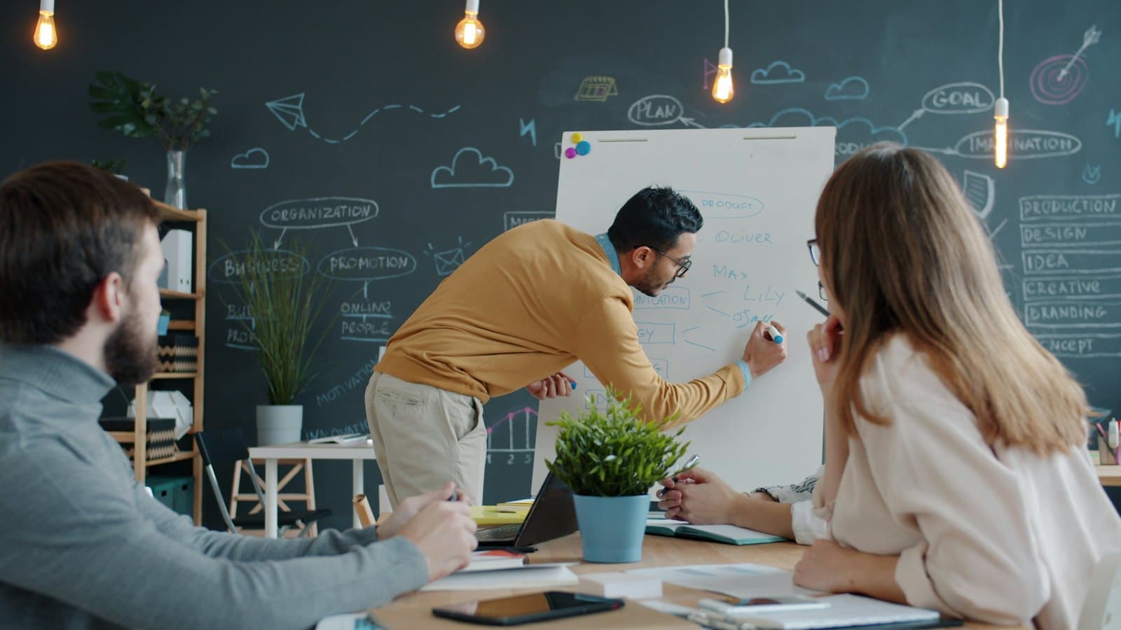 An engineer sketching a product plan on a whiteboard for the team